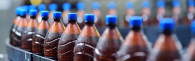 food industrial production of beer. Plastic beer bottles on a conveyor belt against the background of a brewery.