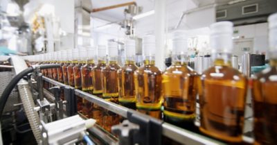 Spill of alcohol in glass bottles at the plant. Conveyor belt with glass bottles. Shop the spillage of alcoholic beverages. The production process of alcoholic beverages