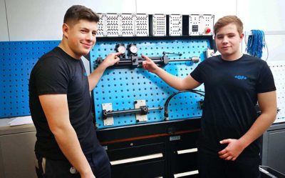 Two trainees in front of a pneumatic system