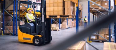 Young workers working together. Woman forklift driver and a man in a warehouse.