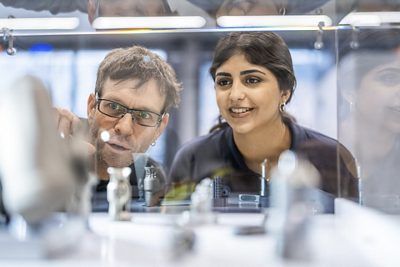 Ein Praxisbildner demonstriert einer Lernenden einen Fertigungsprozess.