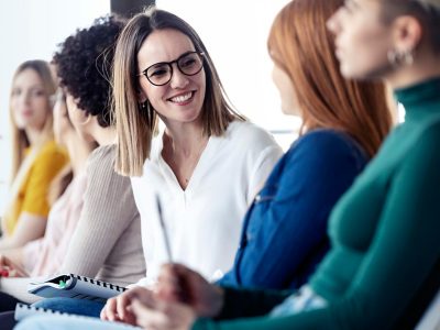 Women sitting in a row of chairs talking to each other