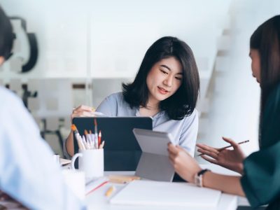 Women sitting a desk look at each others laptops