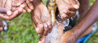 Kids hands scooping water from a fountain on a sunny day 