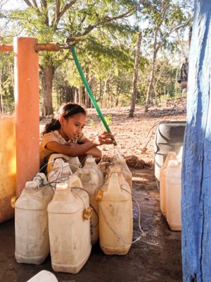 A child fillilng up buckets with water from a pipe in Oemolo