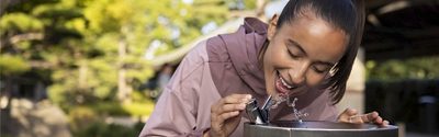 woman drinking water from a water dispenser
