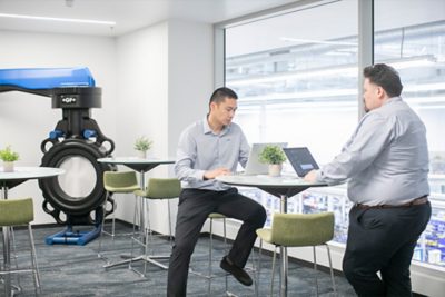 Team members exchanging ideas beside cutting-edge equipment—where precision meets partnership.