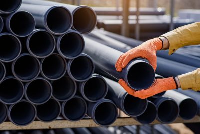 Close up plumber hands choosing a pipe for sewage on a construction site.